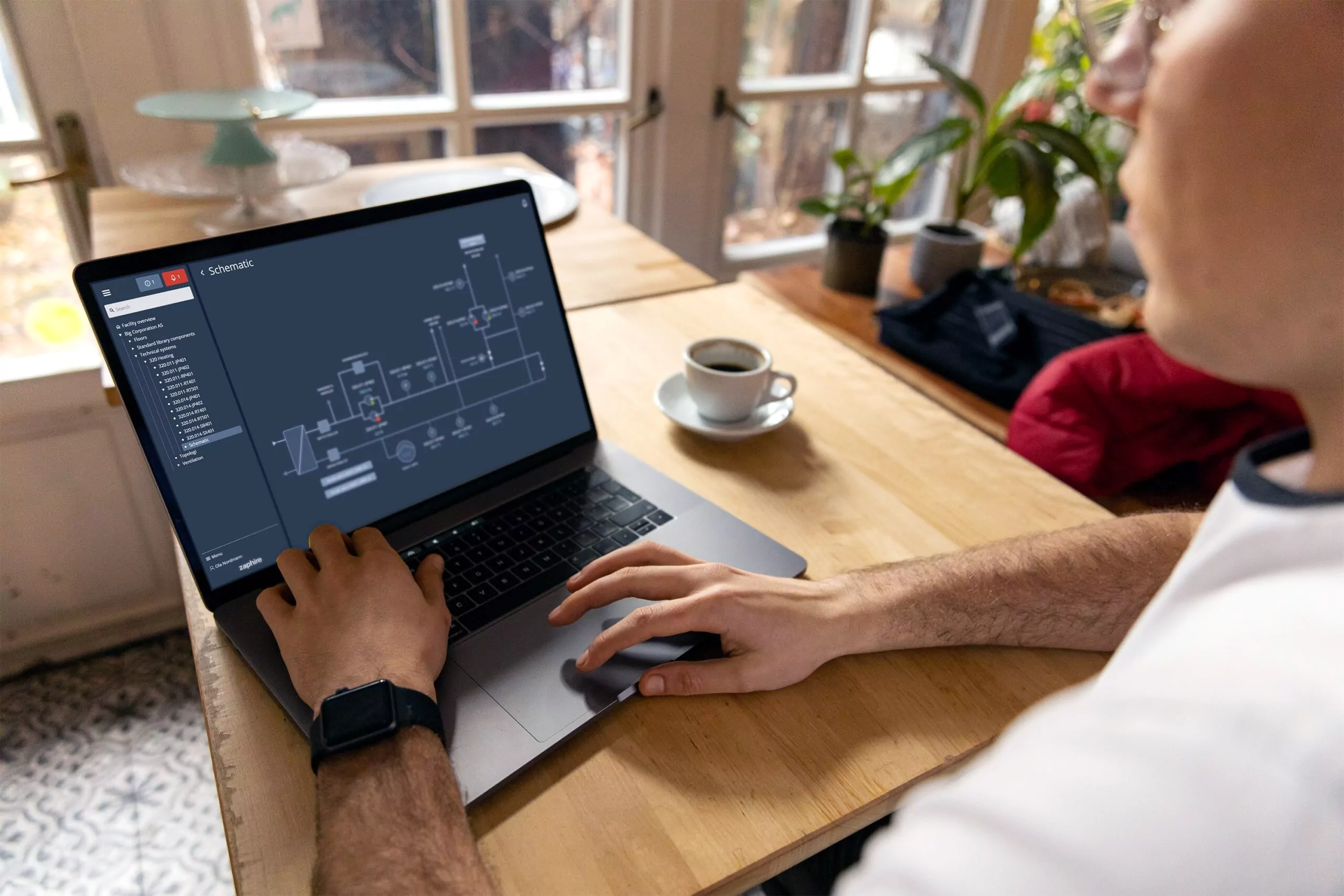 en laptop staar paa et bord. mann sitter foran den og skriver